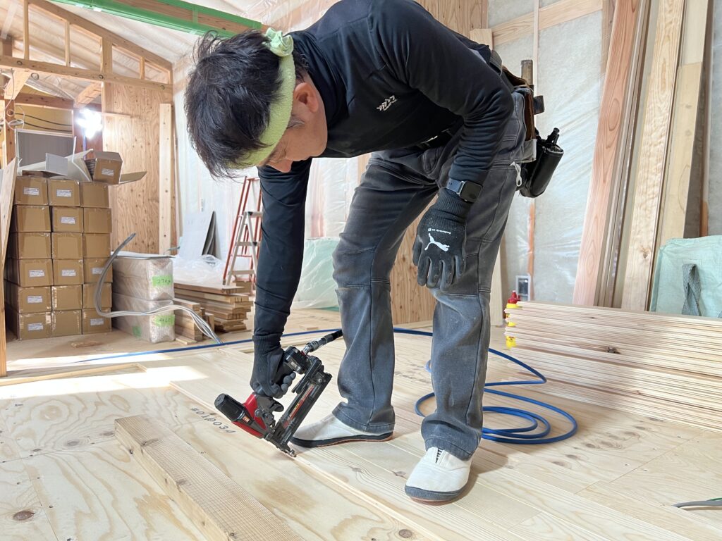 床を打っている大工